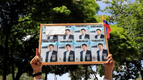 Un hombre sostiene un cartel con propaganda del candidato presidencial Miguel Uribe.